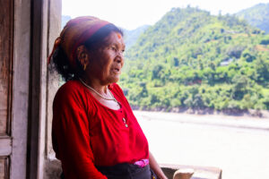 Nanimaya, donna del nepal, vestita di rosso guarda i suoi terreni allagati dall'alluvione